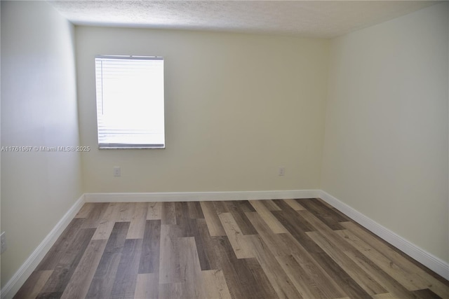 unfurnished room featuring wood finished floors, baseboards, and a textured ceiling