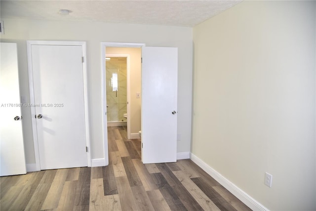 unfurnished bedroom with wood finished floors, baseboards, and a textured ceiling