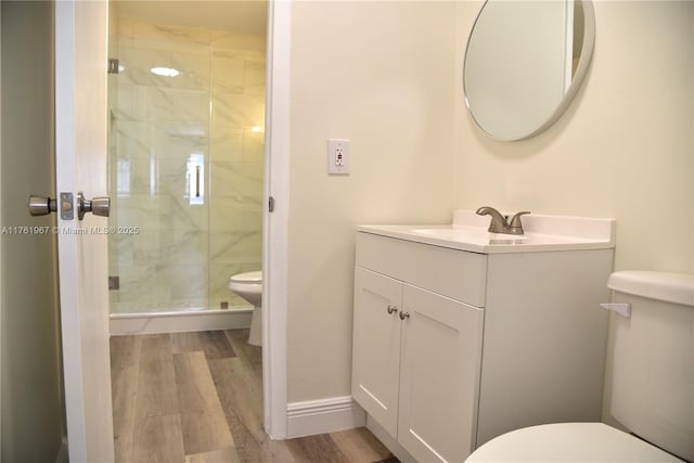 full bath with toilet, wood finished floors, a shower stall, baseboards, and vanity