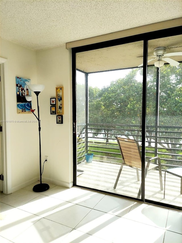 doorway to outside with expansive windows, baseboards, ceiling fan, tile patterned flooring, and a textured ceiling