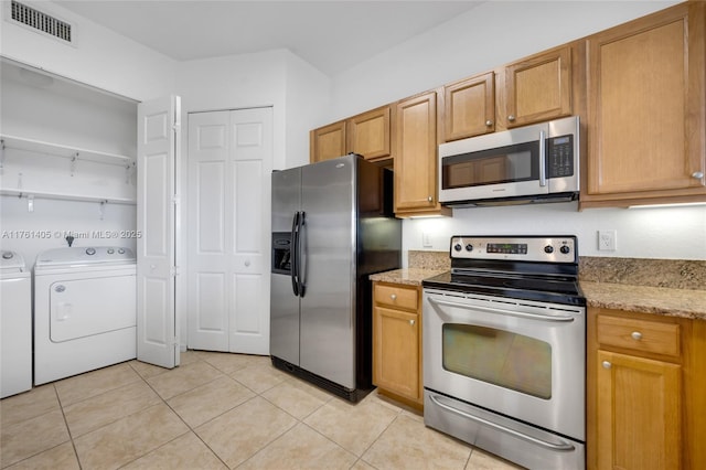 kitchen featuring light stone countertops, independent washer and dryer, stainless steel appliances, light tile patterned flooring, and visible vents
