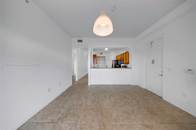 unfurnished room featuring light tile patterned floors, arched walkways, and visible vents