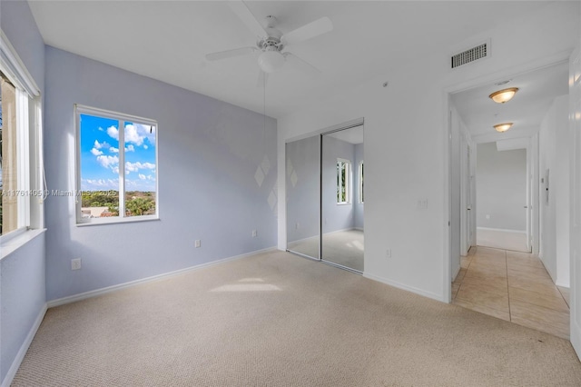 unfurnished bedroom with baseboards, visible vents, a closet, and light colored carpet