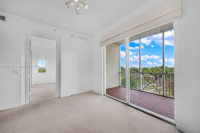 carpeted empty room featuring a healthy amount of sunlight, ceiling fan, and visible vents