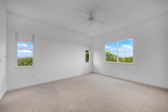 unfurnished room with baseboards, a ceiling fan, and light carpet