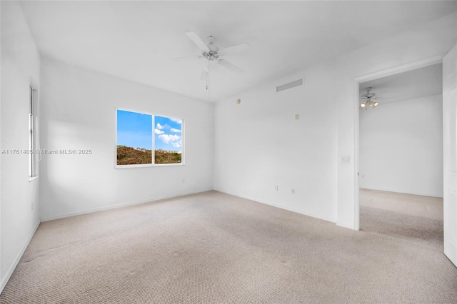 carpeted spare room featuring baseboards, visible vents, and ceiling fan