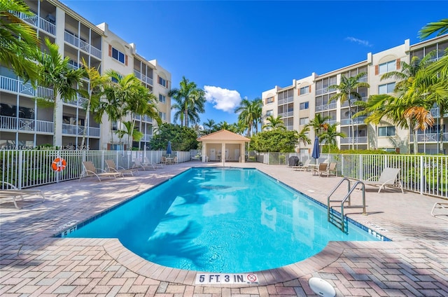 community pool with a patio and fence