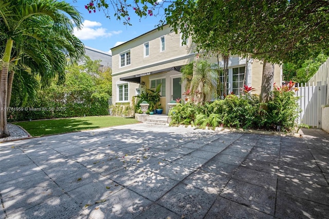 back of property with fence, a lawn, and stucco siding