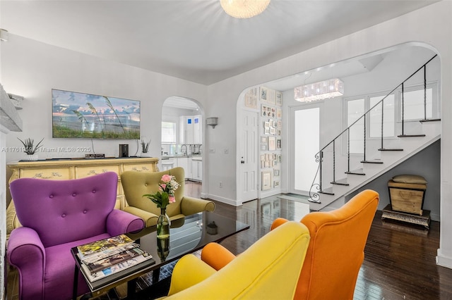 living area featuring arched walkways, stairs, baseboards, and hardwood / wood-style floors