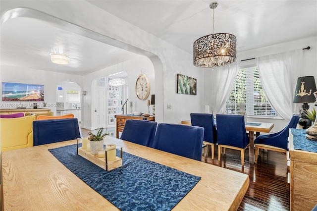 dining room with arched walkways and hardwood / wood-style flooring