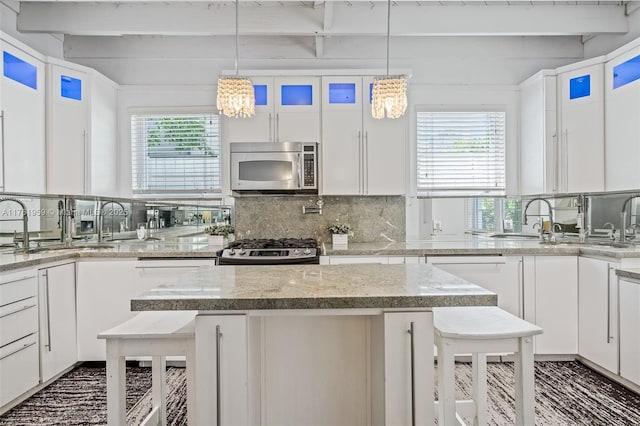 kitchen with tasteful backsplash, white cabinets, appliances with stainless steel finishes, and a breakfast bar