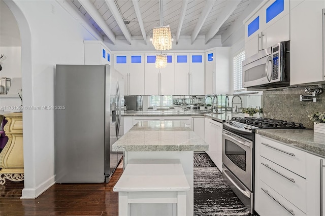 kitchen featuring a kitchen island, stainless steel appliances, decorative backsplash, dark wood-type flooring, and beamed ceiling