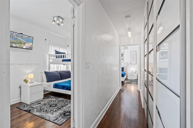 hallway featuring dark wood-type flooring and baseboards