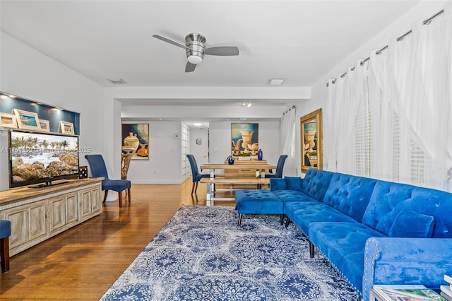 living area with a ceiling fan, wood finished floors, visible vents, and baseboards