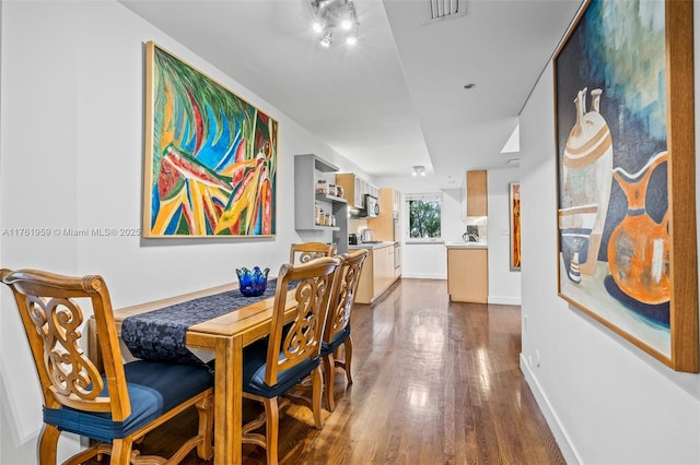 dining space featuring visible vents, dark wood-type flooring, and baseboards