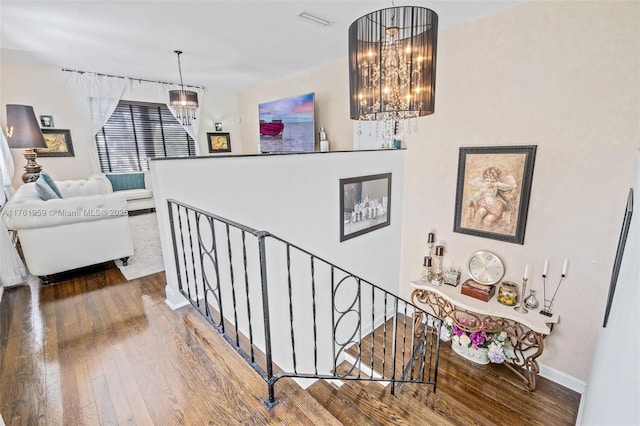 stairway with visible vents, baseboards, an inviting chandelier, and wood-type flooring