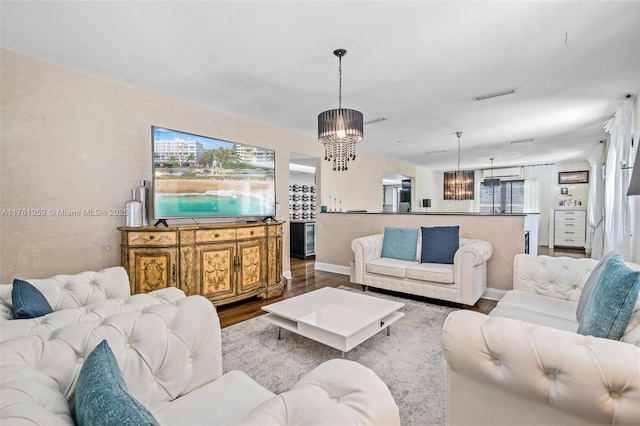 living area with a chandelier, visible vents, baseboards, and wood finished floors