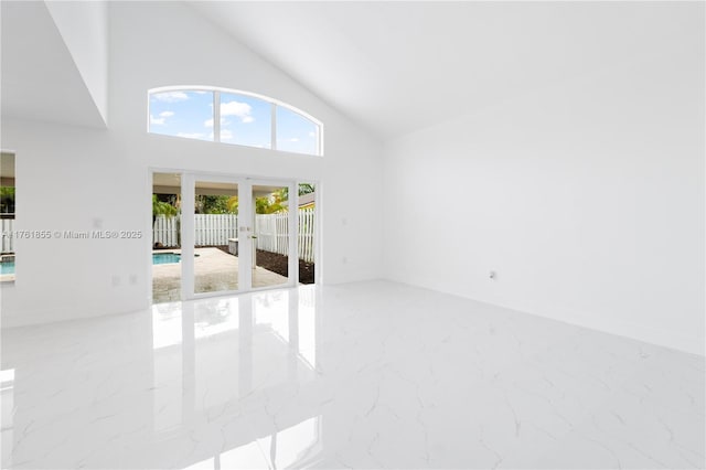 spare room featuring french doors, high vaulted ceiling, and marble finish floor