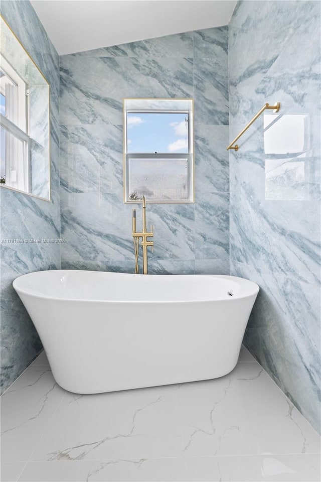 full bath with a soaking tub and marble finish floor