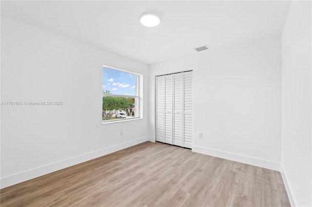 unfurnished room featuring visible vents, light wood-type flooring, and baseboards