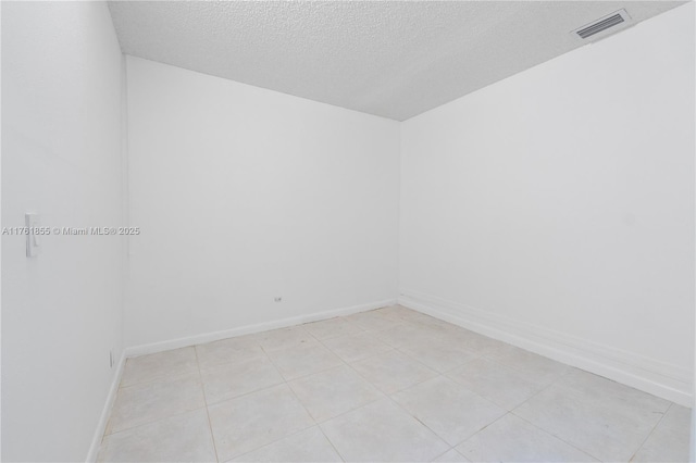 spare room with visible vents, a textured ceiling, and baseboards