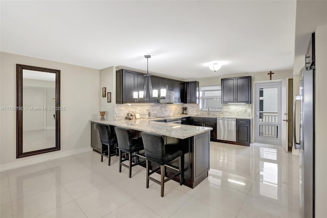 kitchen featuring ventilation hood, a breakfast bar area, decorative backsplash, a peninsula, and stainless steel dishwasher