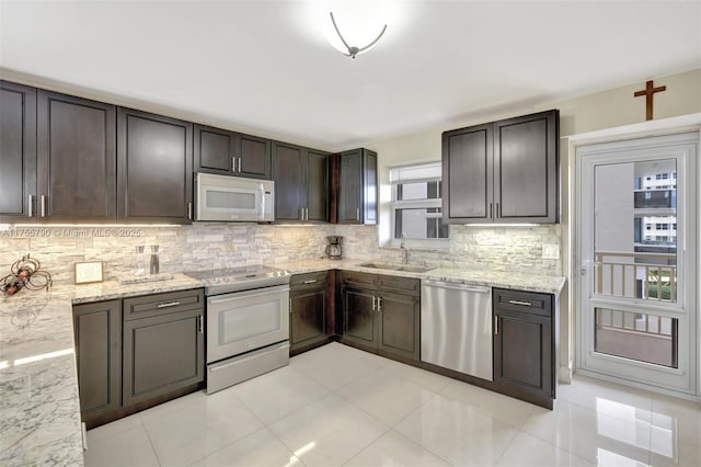 kitchen featuring white microwave, tasteful backsplash, dishwasher, electric range oven, and a sink