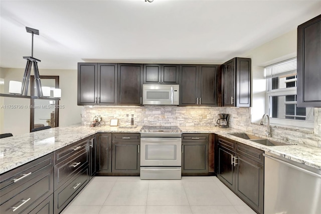 kitchen featuring light stone counters, light tile patterned floors, a sink, appliances with stainless steel finishes, and backsplash