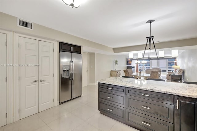 kitchen with light stone countertops, visible vents, light tile patterned flooring, stainless steel refrigerator with ice dispenser, and decorative light fixtures