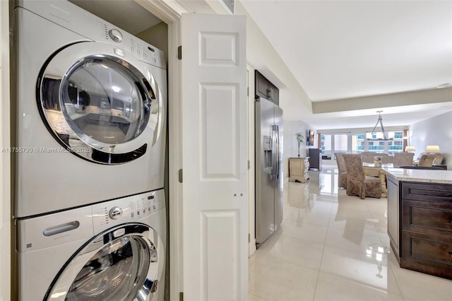 clothes washing area with light tile patterned floors, laundry area, and stacked washing maching and dryer