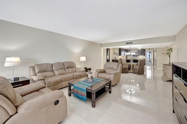 living area featuring light tile patterned floors, visible vents, and a chandelier