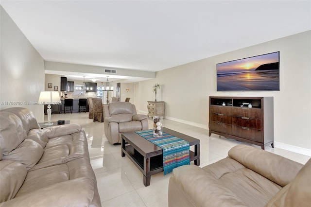 living area with light tile patterned floors, visible vents, baseboards, and an inviting chandelier