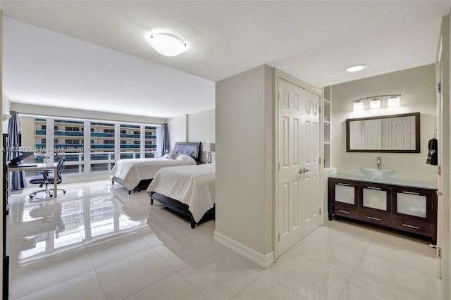 bedroom with a sink, a closet, baseboards, and light tile patterned floors