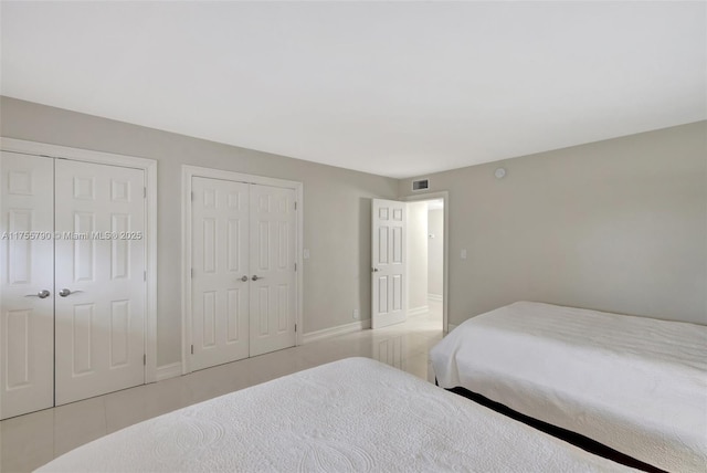 bedroom featuring visible vents, two closets, and baseboards