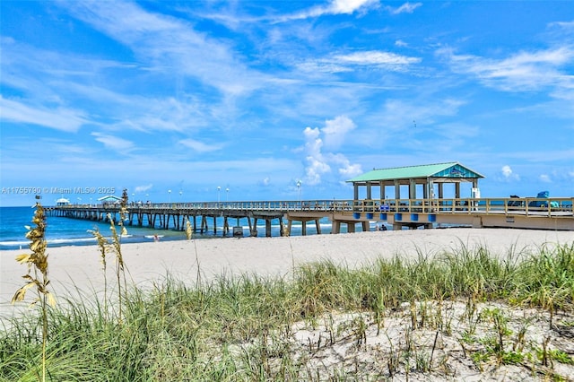 view of dock with a pier, a beach view, and a water view