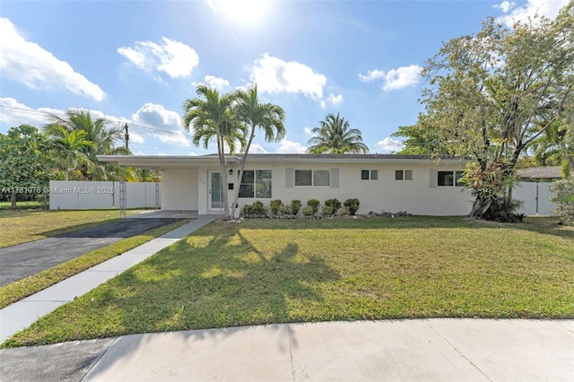 ranch-style house featuring stucco siding, a carport, a front lawn, and fence