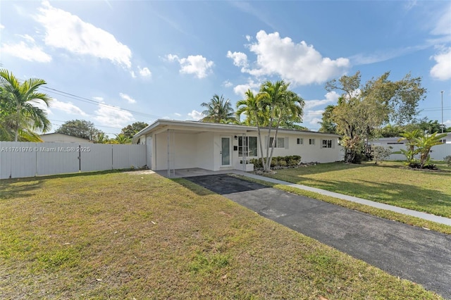 view of front facade with fence, a front yard, stucco siding, a carport, and driveway