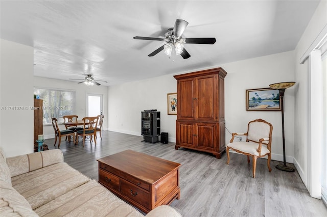 living area with baseboards, light wood finished floors, and ceiling fan