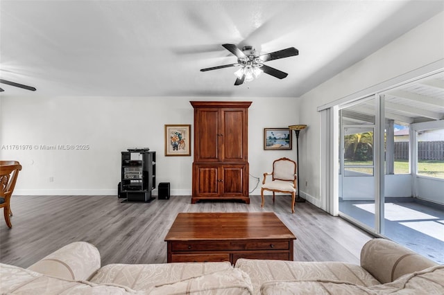 living area featuring baseboards, ceiling fan, and wood finished floors