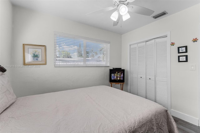 bedroom with visible vents, baseboards, ceiling fan, wood finished floors, and a closet