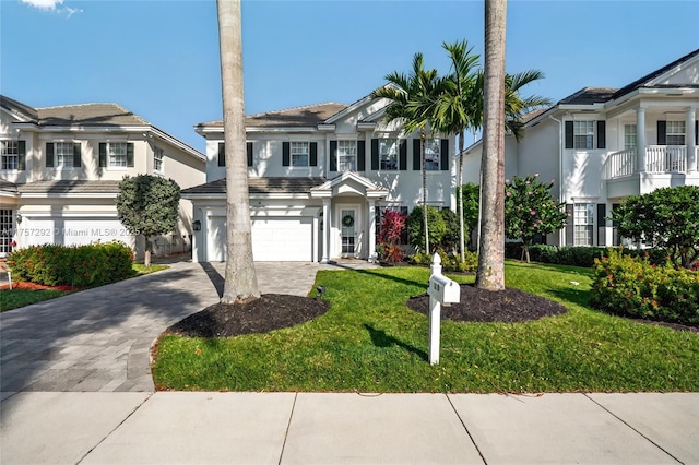 view of front of home featuring stucco siding, an attached garage, decorative driveway, and a front lawn