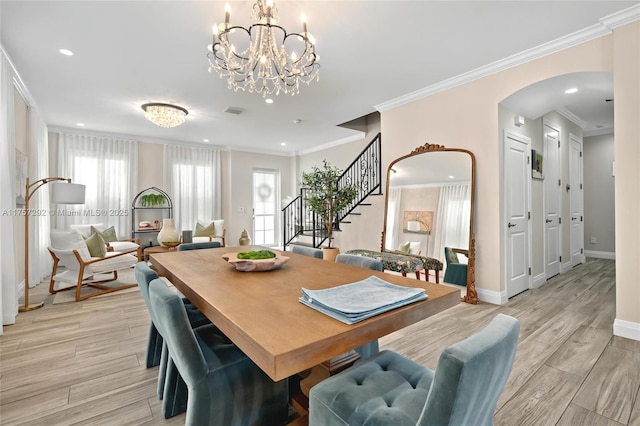 dining space with arched walkways, light wood finished floors, stairs, and baseboards