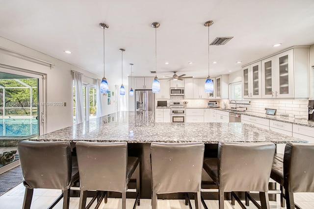 kitchen featuring tasteful backsplash, visible vents, a spacious island, plenty of natural light, and stainless steel appliances