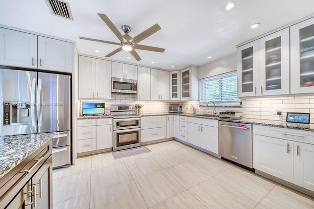 kitchen featuring stone countertops, backsplash, visible vents, and appliances with stainless steel finishes