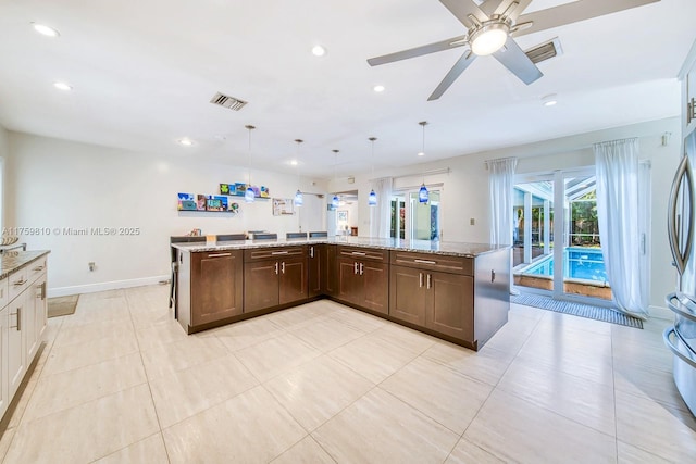 kitchen with dark brown cabinetry, recessed lighting, light stone countertops, and visible vents