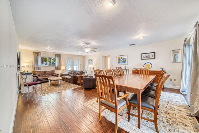 dining room with a ceiling fan, baseboards, visible vents, wood-type flooring, and a textured ceiling