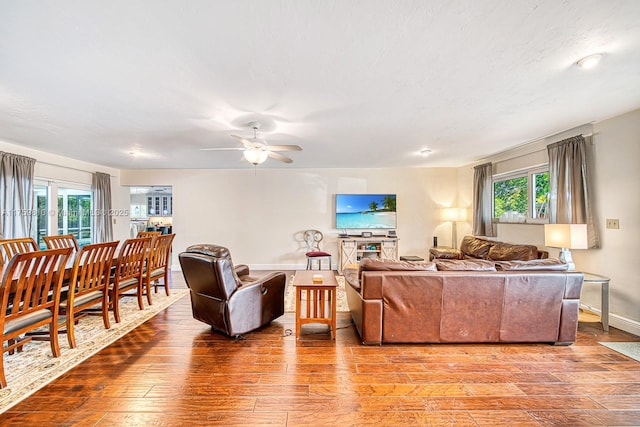 living room featuring a textured ceiling, baseboards, ceiling fan, and wood finished floors