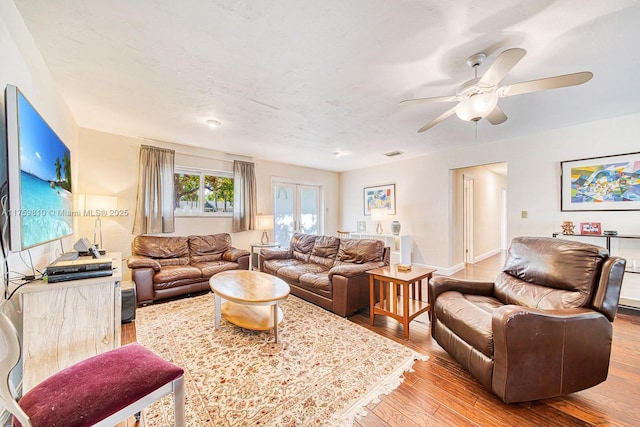 living area featuring visible vents, a ceiling fan, baseboards, and wood finished floors