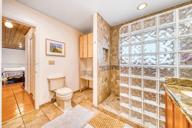 bathroom featuring toilet, a walk in shower, ensuite bath, tile patterned flooring, and baseboards