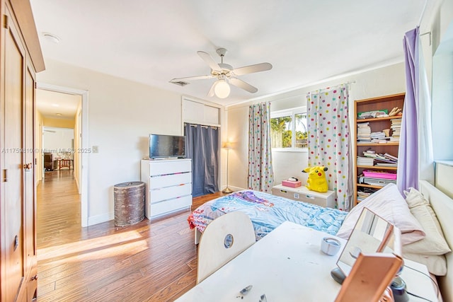 bedroom with visible vents, baseboards, a ceiling fan, and wood finished floors